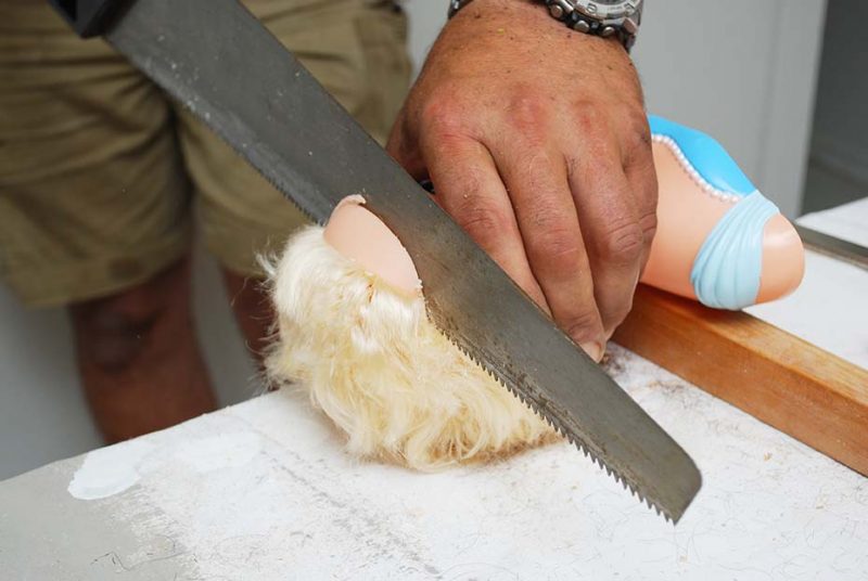 Cutting Off Top Of Doll Head with A Saw